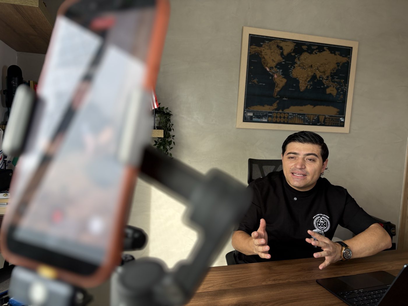 Andrés Castaño frente a la cámara durante una sesión, con un mapa del mundo al fondo.